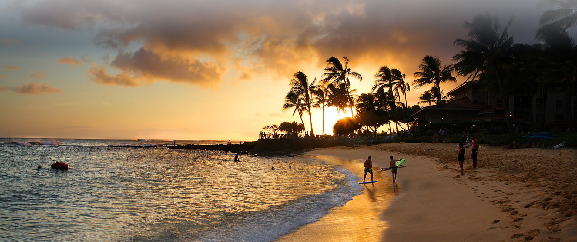 Surfers walking in the sunset on Kauai