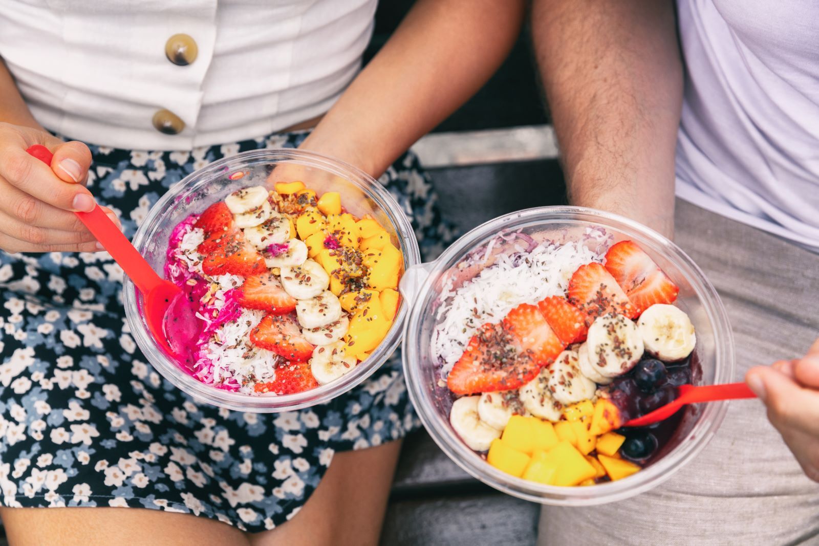 Two people holding acai bowls from restaurant in Kauai, Hawaii